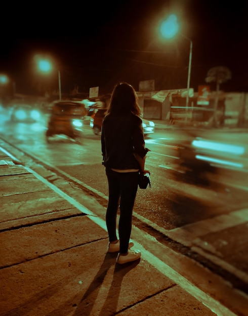 Foto mulher de pé na rua da cidade à noite