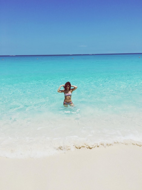 Mulher de pé no mar na praia