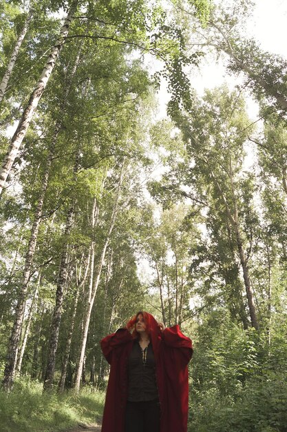 Foto mulher de pé perto de uma árvore na floresta