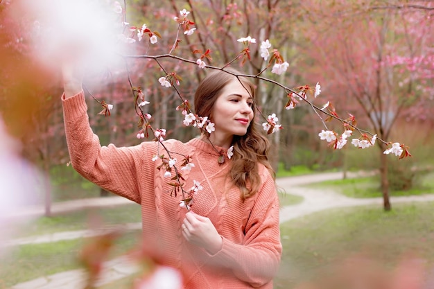 Mulher de pé sob a flor rosa sakura ramo no parque