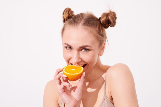 Foto mulher de pele limpa sorridente feliz segurando laranja perto do rosto