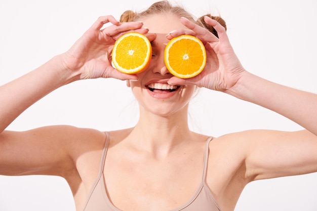 Foto mulher de pele limpa sorridente feliz segurando laranja perto do rosto
