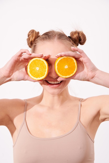 Foto mulher de pele limpa sorridente feliz segurando laranja perto do rosto