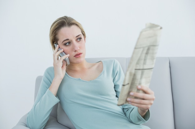 Mulher de pensamento casual telefonando enquanto está sentada no sofá