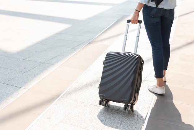 Mulher de perto e carrinho de malas bagagem no aeroporto Pessoas e estilos de vida conceito de viagem e viagem de negócios tema Mulher usar jeans indo em turnê e viajando ao redor do mundo por sozinha garota