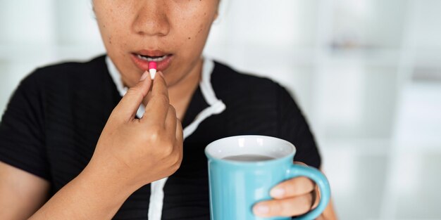 Mulher de perto segurando um comprimido na mão com água sentindo-se doente Mulher vai tomar analgésico de dor de cabeça analgêsico cuidados de saúde medicina tratamento terapia paciente doença conceito de doença