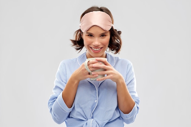 Foto mulher de pijama e máscara de dormir a beber café.