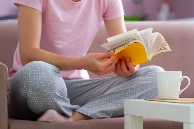 Mulher de pijama está descansando e lendo um livro favorito em casa