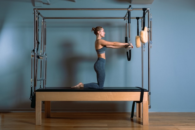 Mulher de pilates fazendo exercícios de provocação do reformador na academia dentro de casa