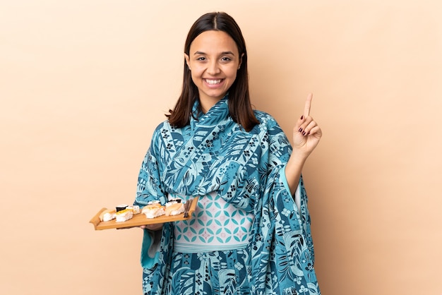 Mulher de quimono segurando sushi sobre um fundo isolado apontando uma ótima ideia