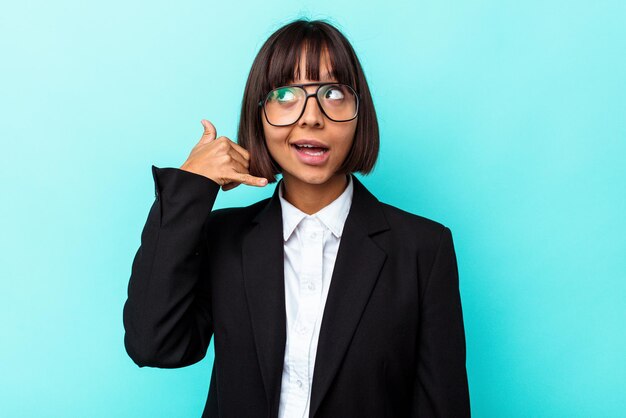 Mulher de raça mista de negócios jovem isolada em fundo azul, mostrando um gesto de chamada de telefone móvel com os dedos.