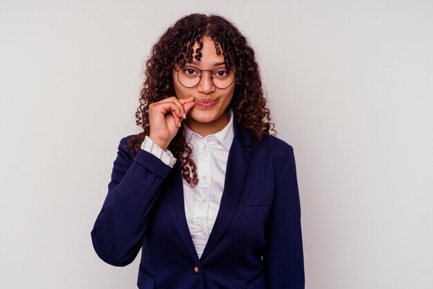 Mulher de raça mista de negócios jovem isolada no fundo branco com os dedos nos lábios, mantendo um segredo.