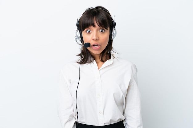 Mulher de raça mista de telemarketing trabalhando com um fone de ouvido isolado no fundo branco com expressão facial de surpresa