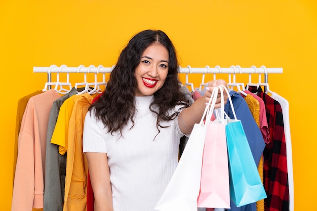 Mulher de raça mista em uma loja de roupas e com sacolas de compras