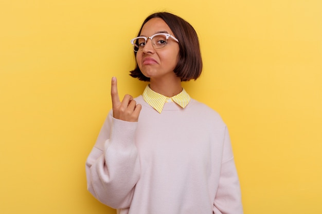 Mulher de raça mista jovem estudante isolada em fundo amarelo apontando com o dedo para você como se fosse um convite para se aproximar.