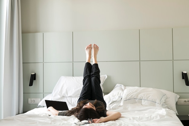 Mulher de refrigeração deitada na cama com as pernas para cima