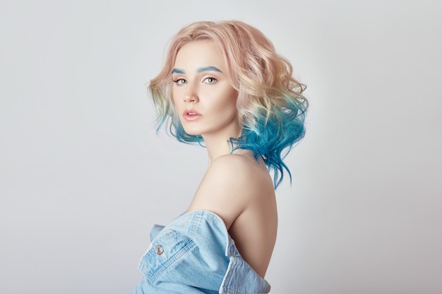 Mulher de retrato com cabelo voador de cor brilhante, todos os tons de azul púrpura. Coloração de cabelo, belos lábios e maquiagem. Cabelo esvoaçando ao vento. Garota sexy com cabelo curto