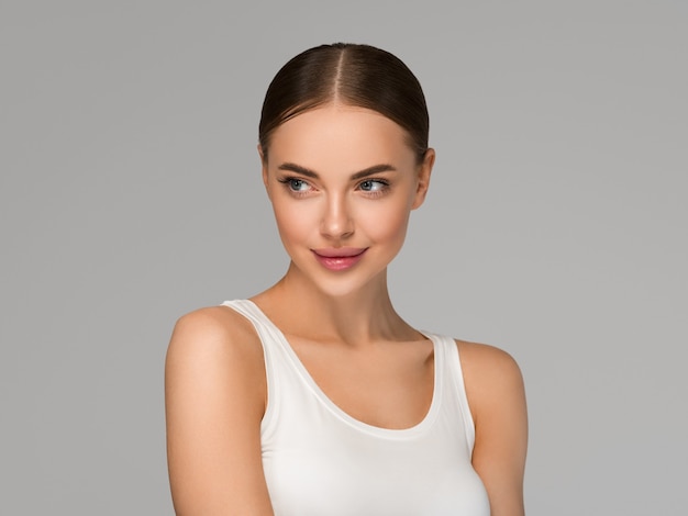 Mulher de rosto de pele bonita natural maquiagem modelo feminino de beleza de pele saudável. Cor de fundo. cinzento