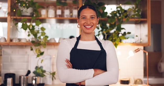 Mulher de rosto e barista com braços cruzados sorriso e confiança no sucesso da loja e garçonete no café Retrato funcionária ou senhora com felicidade empreendedora ou proprietária de negócios na cafeteria