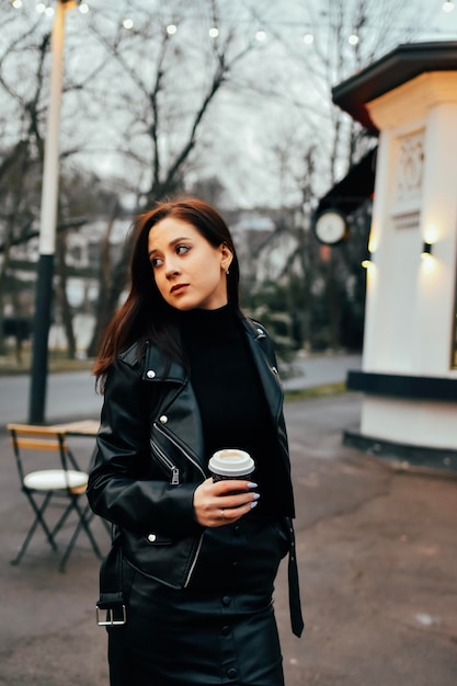 Mulher de roupa preta tomando café no parque