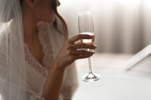 mulher de roupão de casamento branco segurando a taça de champanhe na mão