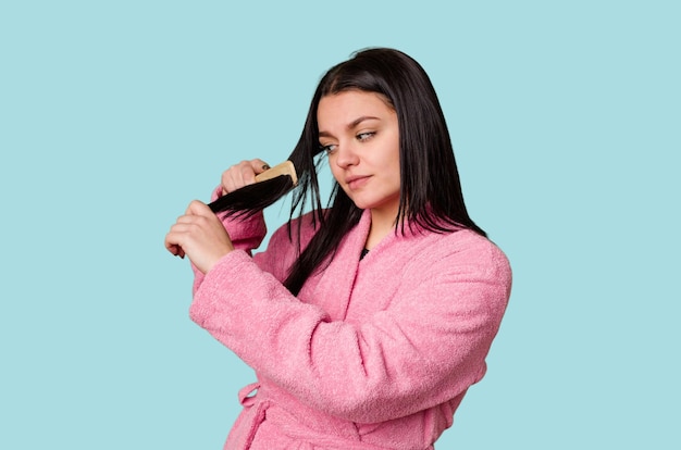 Mulher de roupão rosa se preparando arrumando o cabelo com um pente parecendo bonita