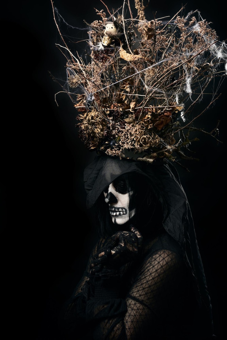 Foto mulher de roupas pretas e maquiagem de crânio uma coroa de galhos secos e flores em sua cabeça