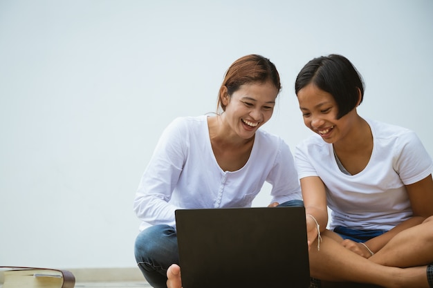 Mulher de Ásia e menina usando computador notebook juntamente com diversão e feliz