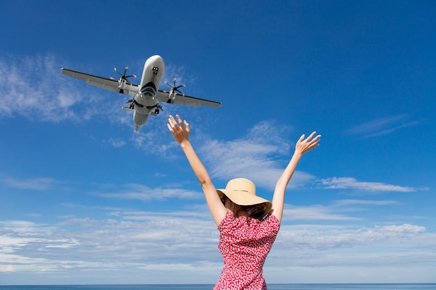 Mulher de Ásia viajando olhando para o avião voando acima do mar