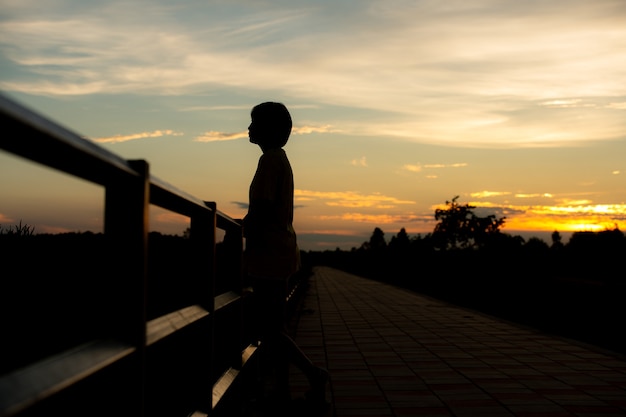 Silhueta de mulher triste preocupado ao pôr do sol