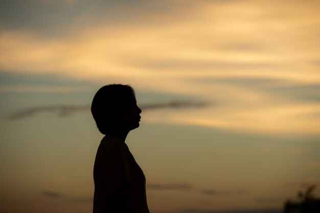 Mulher de silhueta com tristeza ao pôr do sol sozinho.