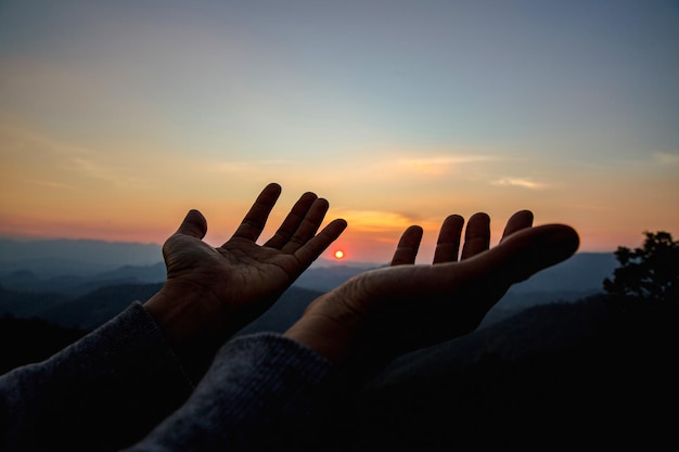 Mulher de silhueta em fundo por do sol. Mulher levantando as mãos em adoração.