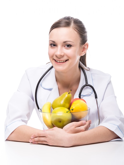 Mulher de sorriso nova no uniforme médico com frutas.