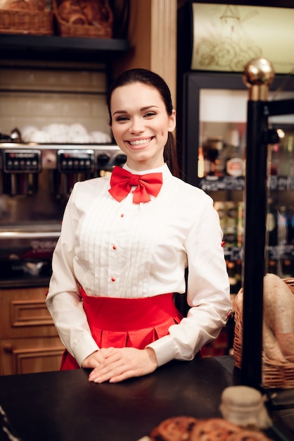 Mulher de sorriso nova que está na padaria moderna.