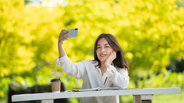 Mulher de sorriso pensativo no parque usando tablet digital inteligente Retrato de um jovem negócio encantador