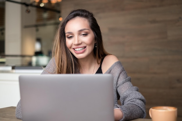 Mulher de sorriso que usa o telefone em casa