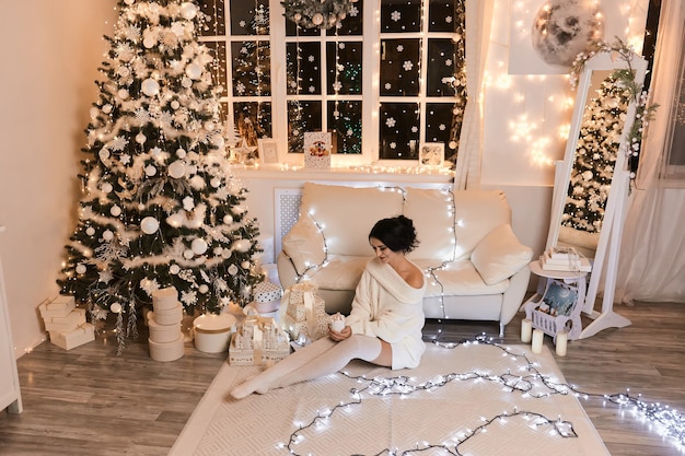 Mulher de suéter branco, noite quente e aconchegante em design de interiores de Natal