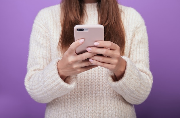 Mulher de suéter está segurando um telefone em uma caixa rosa