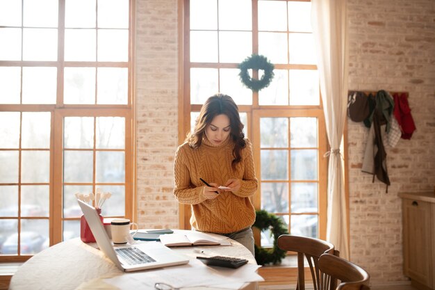 Foto mulher de suéter trabalhando em um laptop