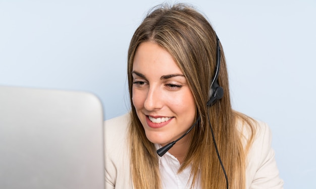 Mulher de telemarketing loira jovem sobre parede azul isolada e sorrindo