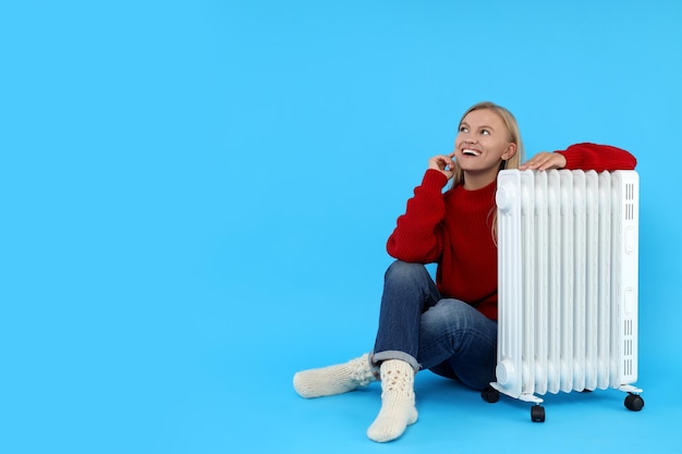 Mulher de temporada de aquecimento com aquecedor em fundo azul