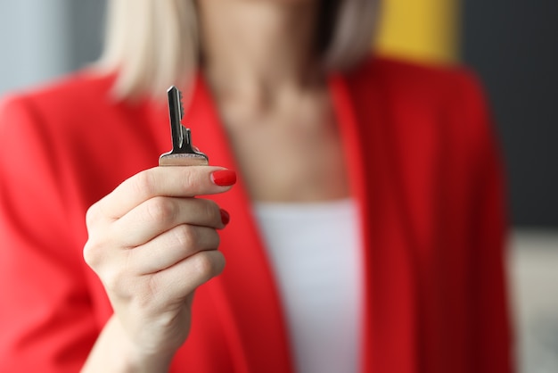 Mulher de terno vermelho segurando uma chave de aço em close-up do escritório