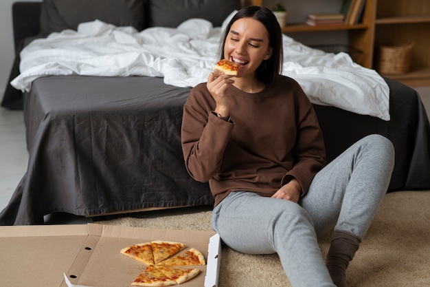 Mulher de tiro completo comendo pizza deliciosa