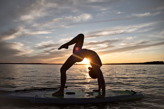 Mulher de tiro completo fazendo ioga no paddleboard