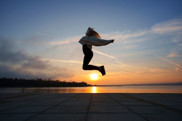 Foto mulher de tiro completo posando ao pôr do sol