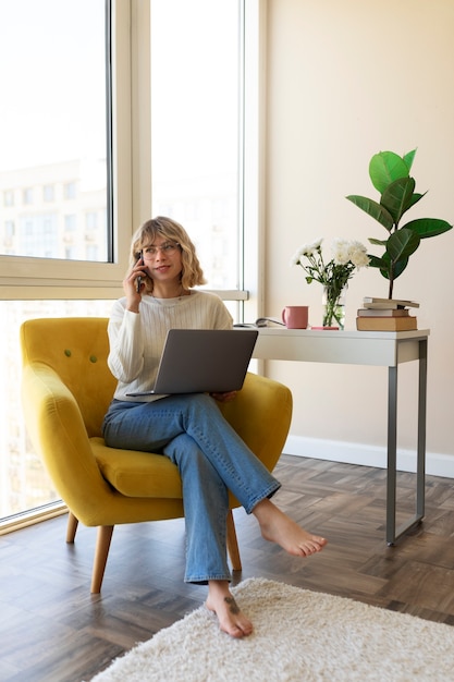 Mulher de tiro completo sentada na cadeira com laptop