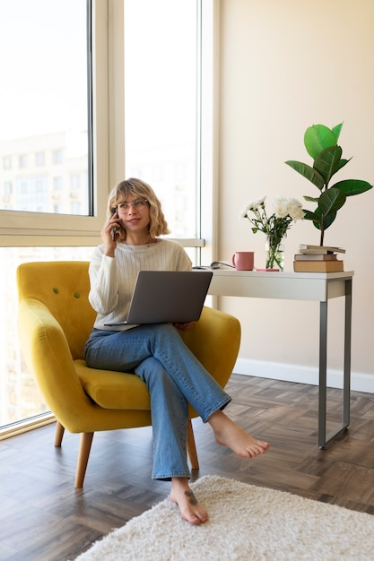 Foto mulher de tiro completo sentada na cadeira com laptop