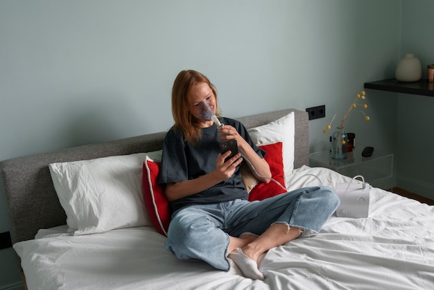 Mulher de tiro completo usando nebulizador em casa