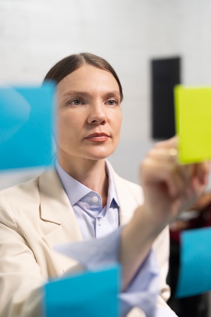 Mulher de tiro médio colando post-it na janela