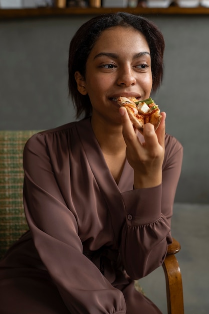 Mulher de tiro médio comendo pizza deliciosa